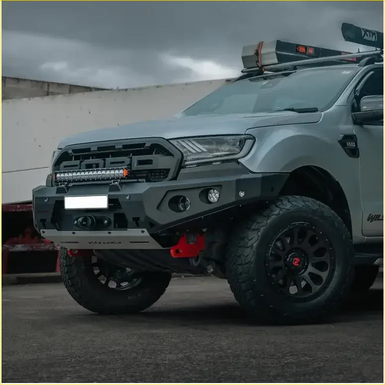 Gray ford ranger with rugged front bumper black off-road tires and roof rack featuring rockarmor rock pack gt hoopless bullbar and rock sliders