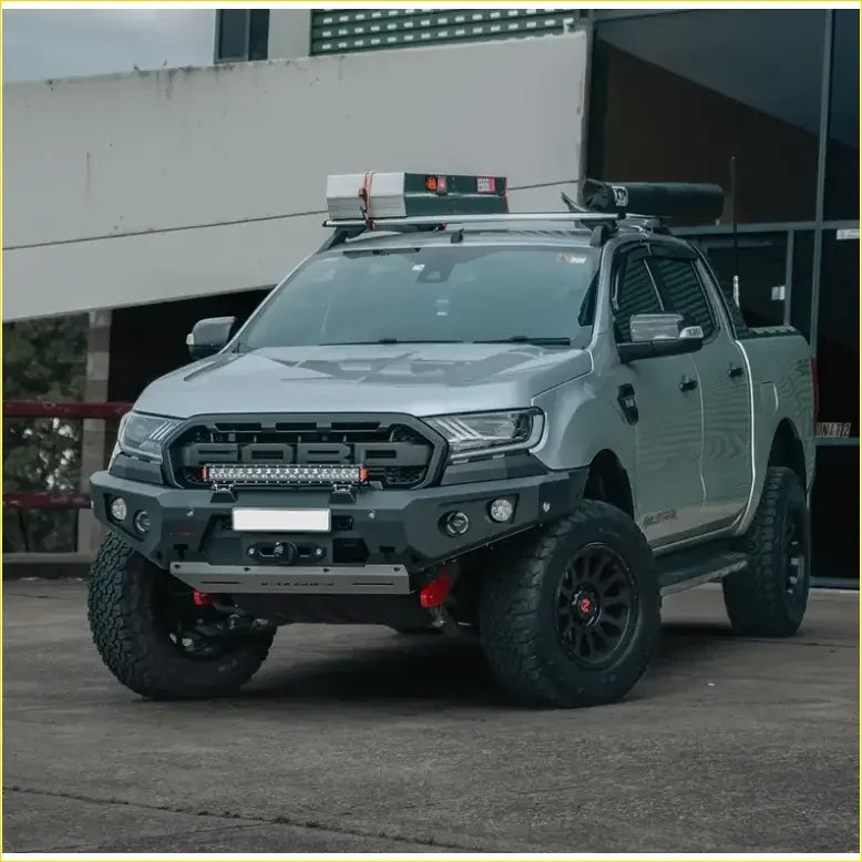 Silver ford ranger with black off-road tires and rugged front bumper featuring gt hoopless bullbar rock sliders